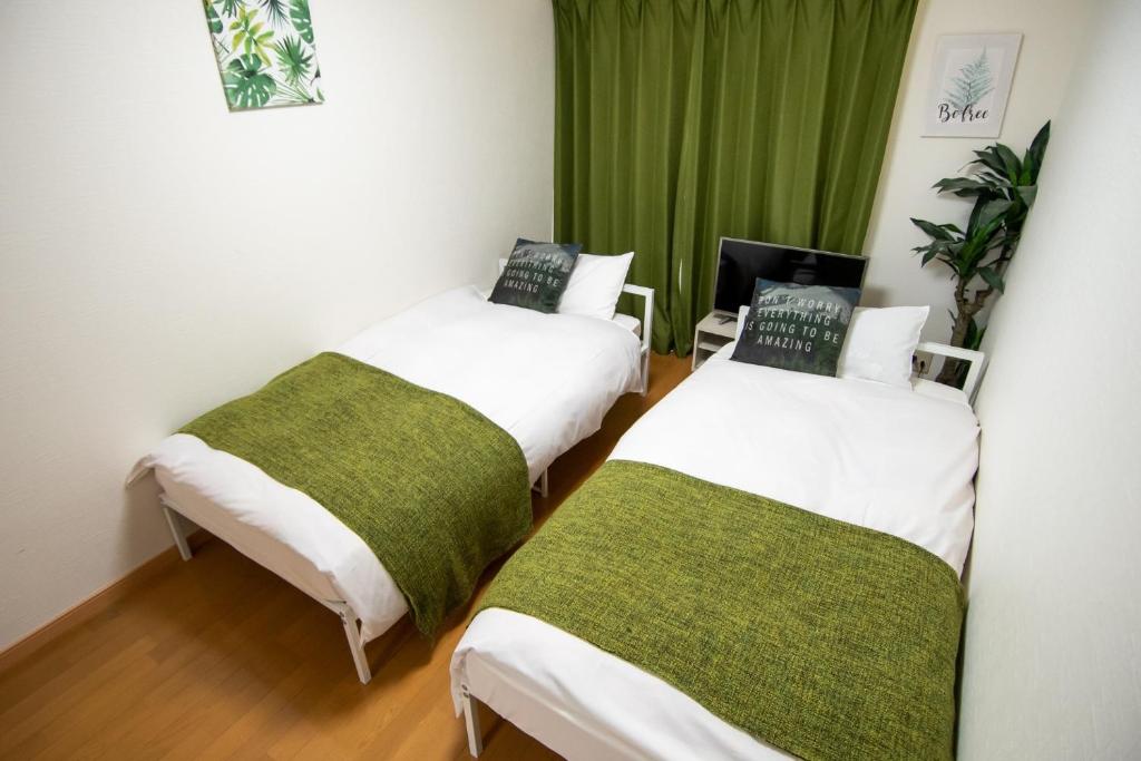 2 Betten in einem Zimmer mit grünen Vorhängen in der Unterkunft MELL-THEATHER - Vacation STAY 10360 in Osaka