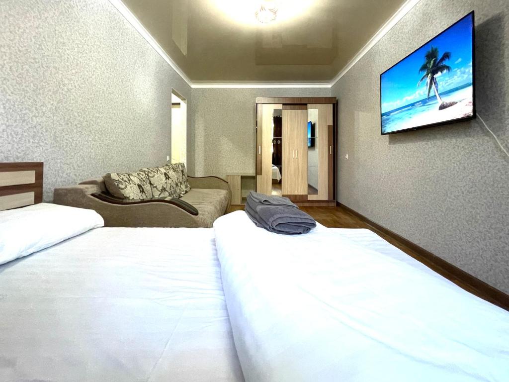 ein Hotelzimmer mit 2 Betten und einem Flachbild-TV in der Unterkunft Абая 68 квартира в центре, 4 спальных места in Petropawlowsk