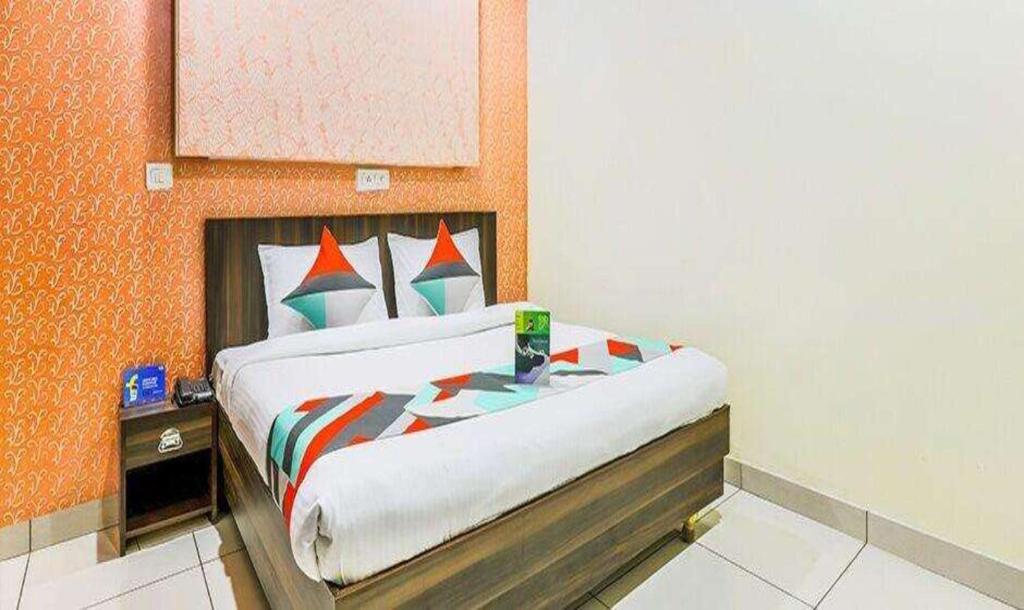 a bedroom with a large bed with an orange wall at FabExpress Mayank Palace in Chandīgarh