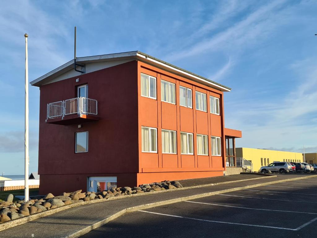 um edifício vermelho com uma varanda num parque de estacionamento em The Old Post Office Guesthouse em Grundarfjordur