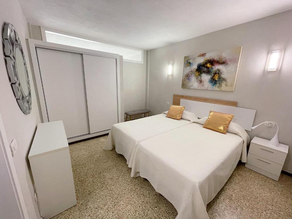 a white bedroom with a bed and a window at Edificio Playa in Los Cristianos