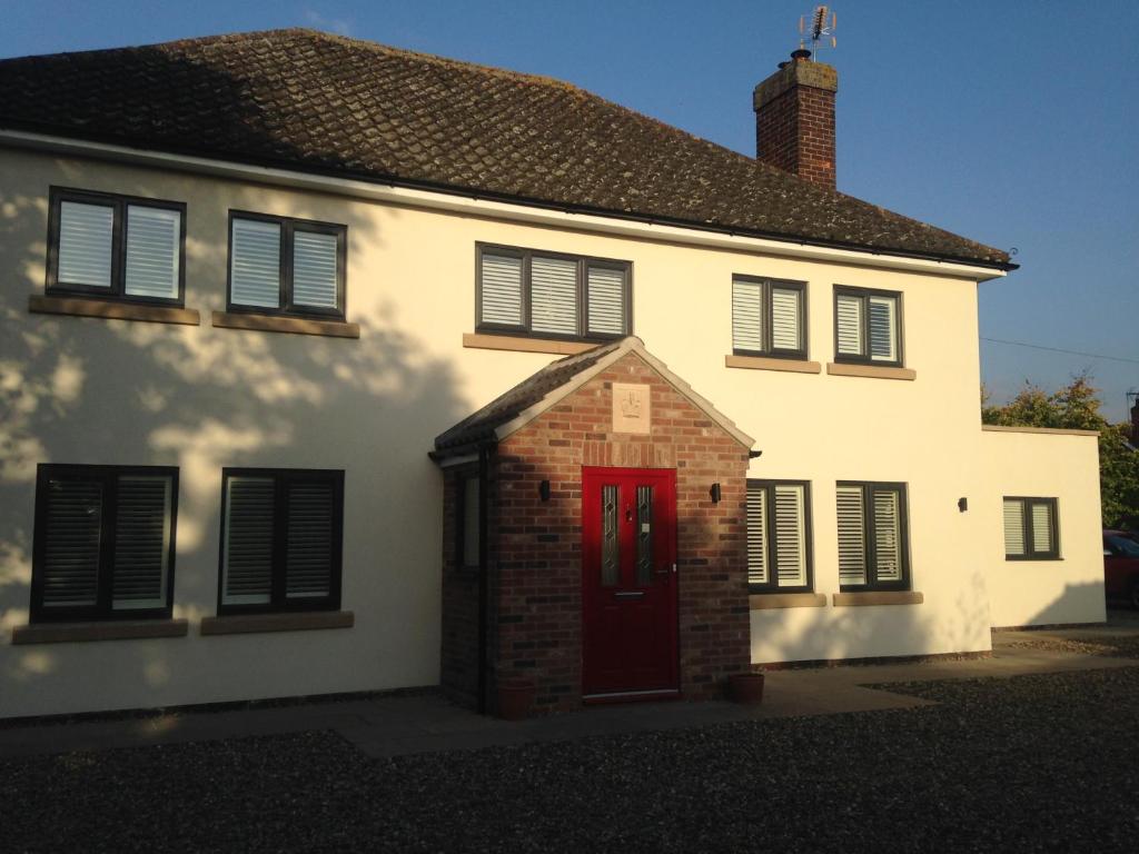 ein weißes Haus mit einer roten Tür und schwarzen Rollläden in der Unterkunft Cherry Farmhouse in York