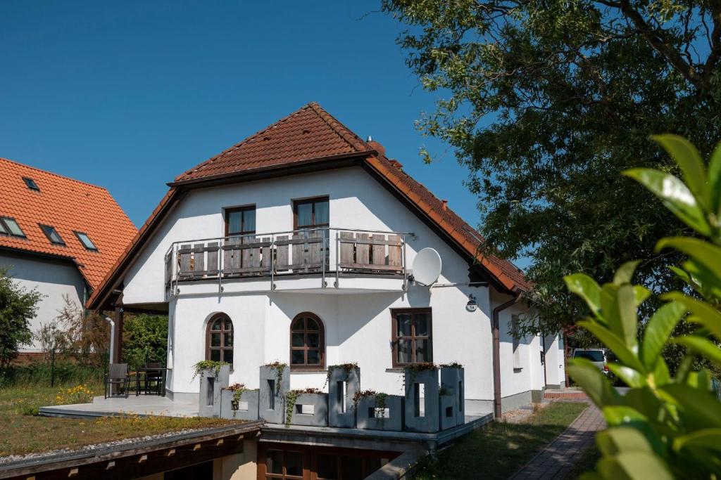 a white house with a balcony on top of it at Ackerweg Ferienwohnungen in Ueckeritz