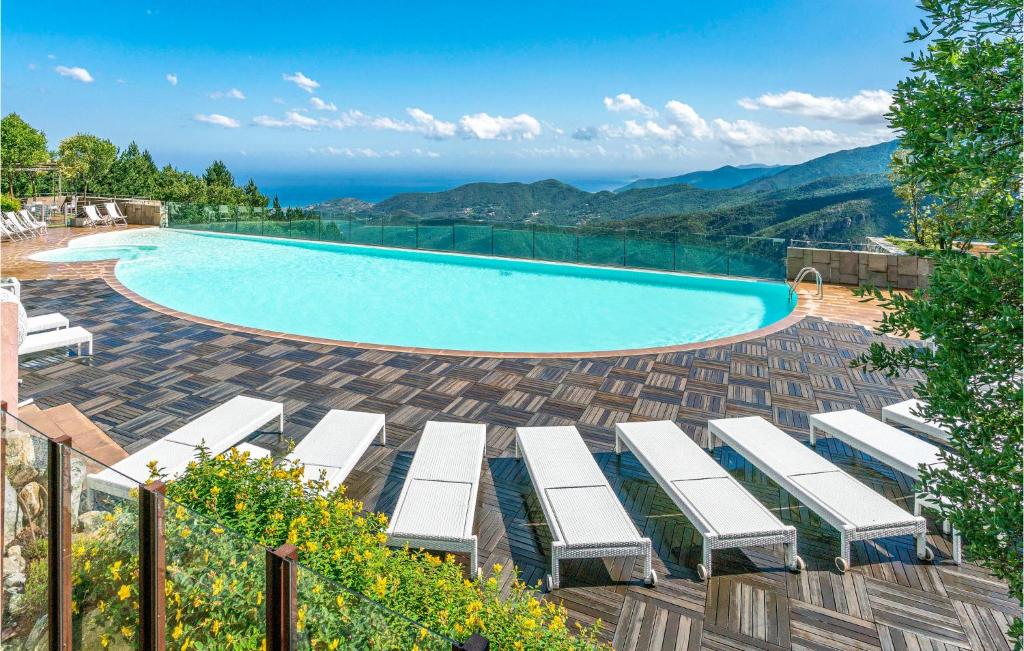 - une piscine avec des chaises longues et des montagnes dans l'établissement Amazing Home In Magliolo With House A Panoramic View, à Magliolo