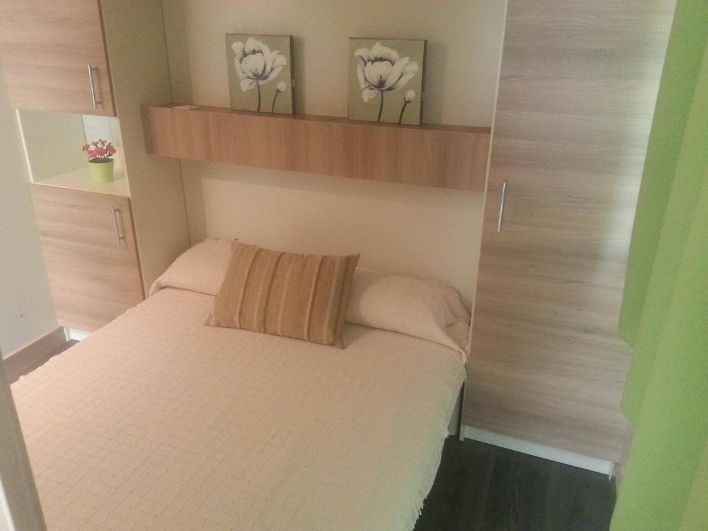 Un pequeño dormitorio con una cama blanca y estanterías en Camping Covadonga, en Soto de Cangas