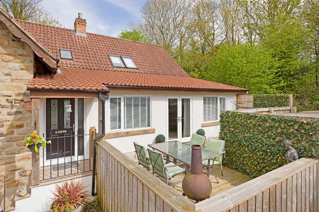 a house with a deck with a table and chairs at Port Arthur Cottage in Knaresborough