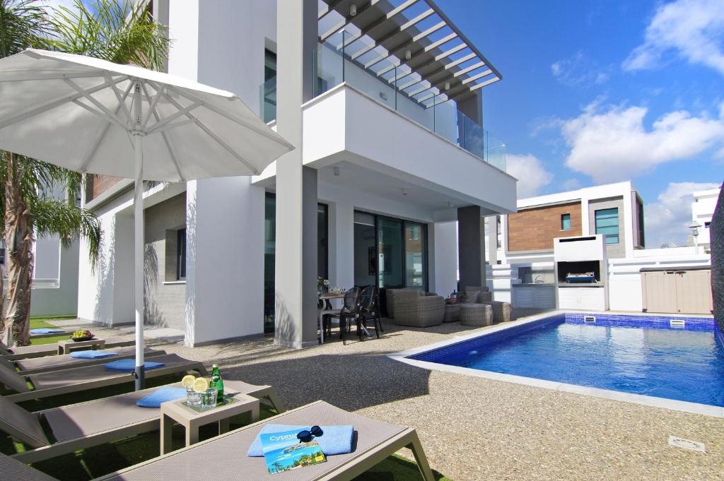 eine Villa mit einem Pool und einem Sonnenschirm in der Unterkunft Villa Mey in Protaras