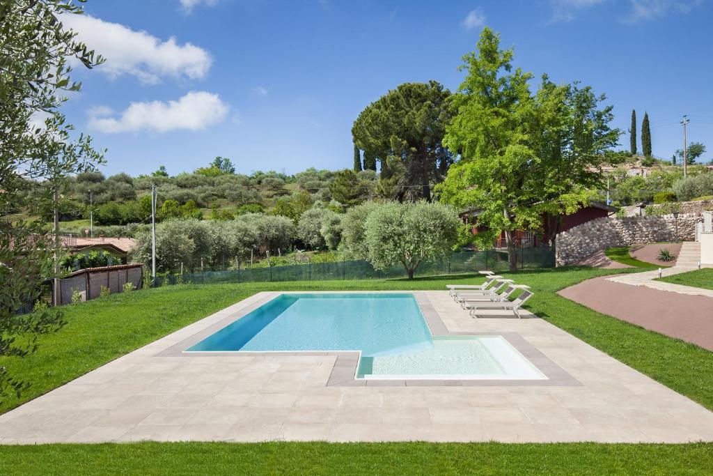 einen Pool in einem Garten mit Gras und Bäumen in der Unterkunft Villa Chiara APT 1- Appartamento in villa con piscina in Cavaion Veronese