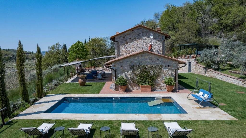 a pool in a yard with chairs and a building at Casa Perano in Gaiole in Chianti
