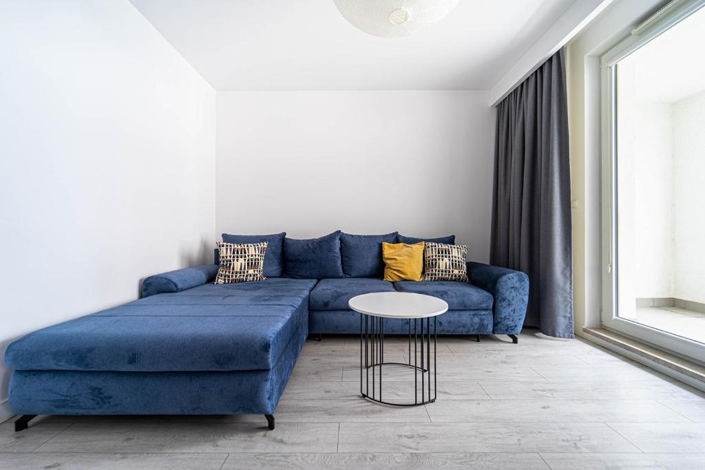 a living room with a blue couch and a table at Kolska Grey Apartment in Warsaw
