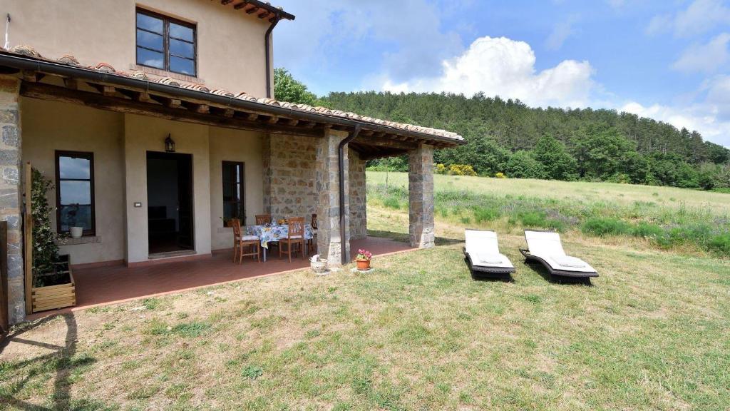 a house with two lounge chairs in the yard at Ginepro in Roccalbegna