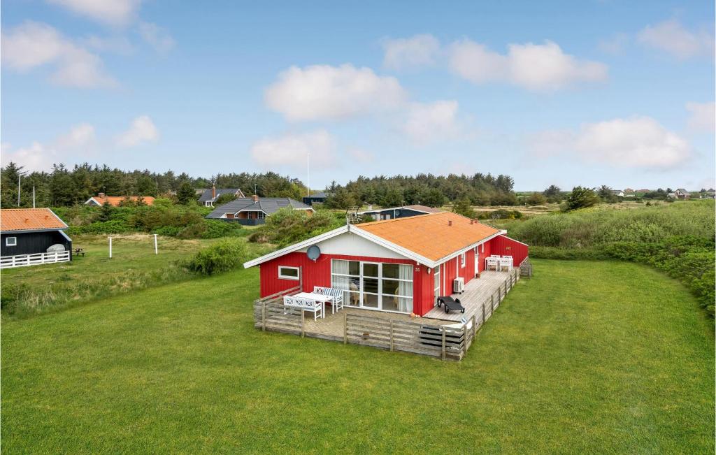 a red house on a large grass field at Stunning Home In Harbore With House A Panoramic View in Harboør
