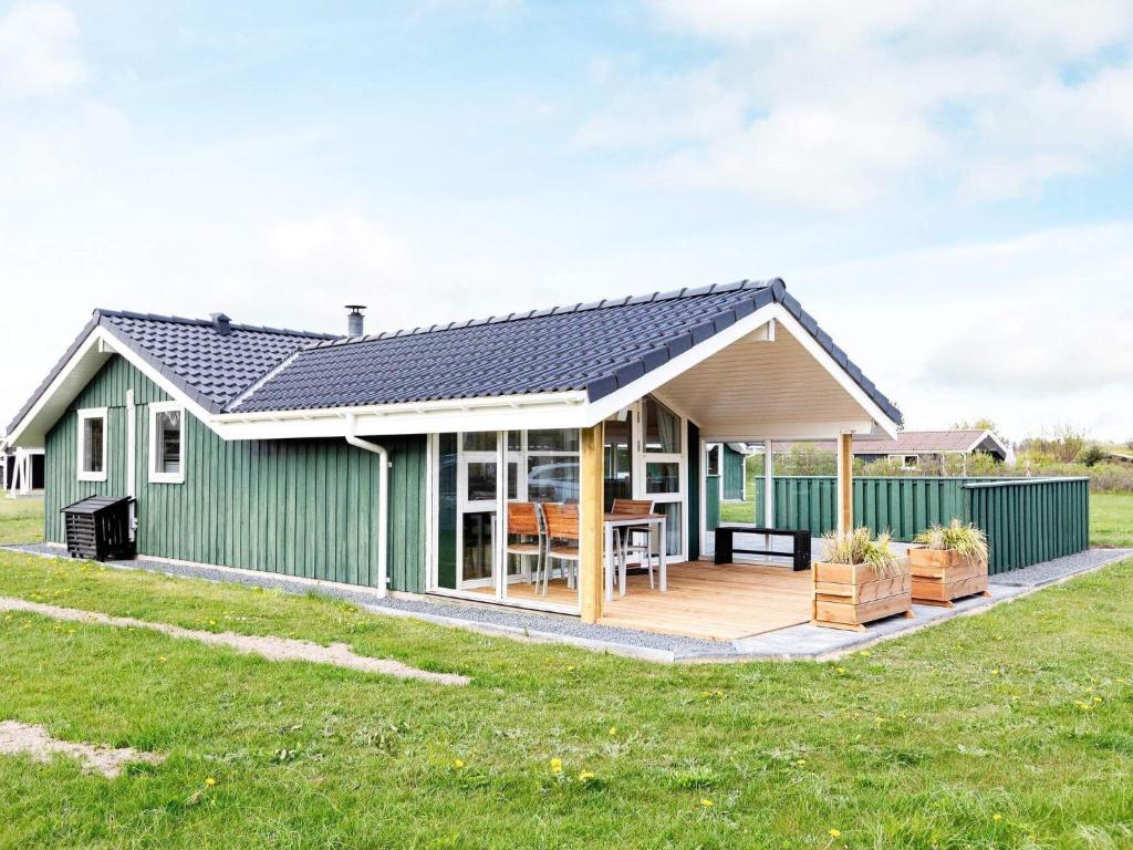 una casa verde con terraza y una casa en 6 person holiday home in Hj rring en Lønstrup
