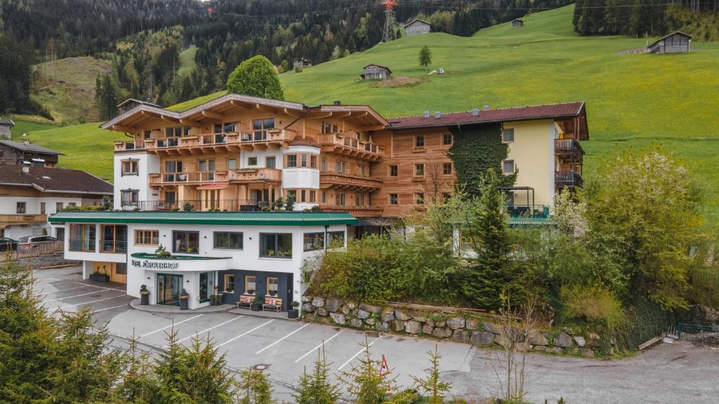 a large building with a green hill in the background at Ferienhotel Jörglerhof in Hainzenberg