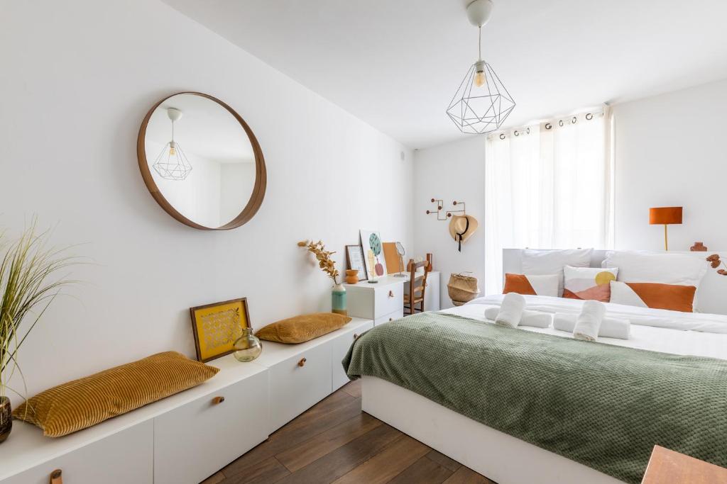 - une chambre blanche avec un grand lit et un miroir dans l'établissement 90m2 renové - terrasse en plein coeur de marseille, à Marseille