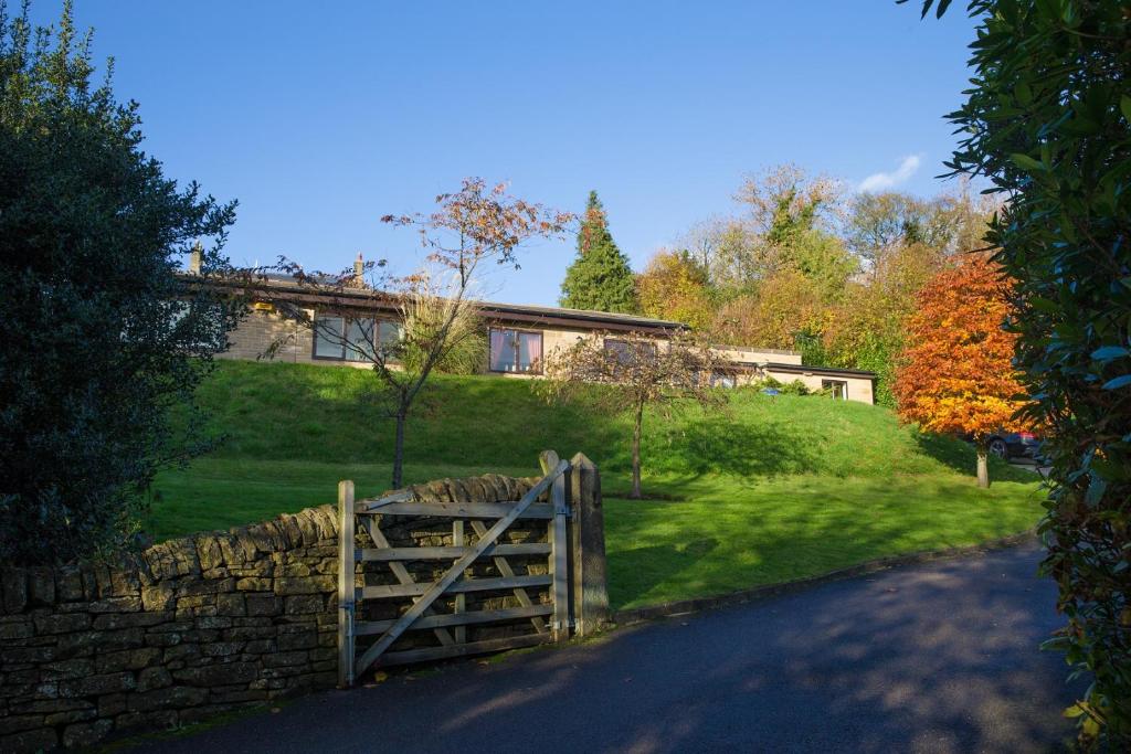 a house with a wooden gate and a stone fence at Sladen Lodge in Hathersage
