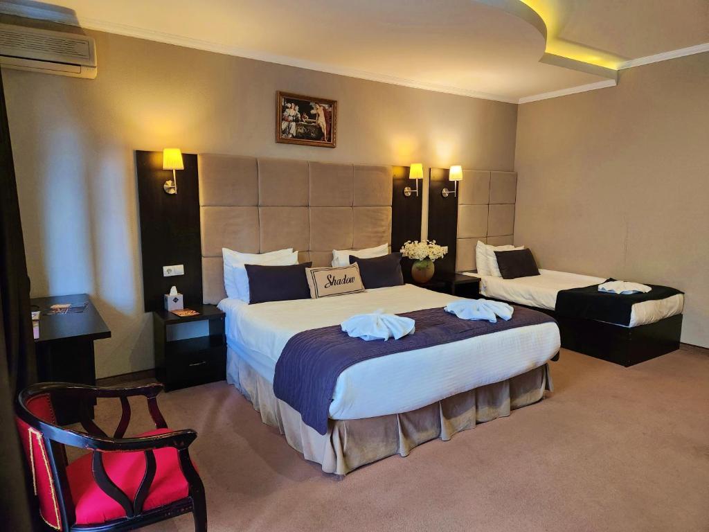 una habitación de hotel con 2 camas y una silla en Shadow Boutique Hotel & SPA, en Chişinău