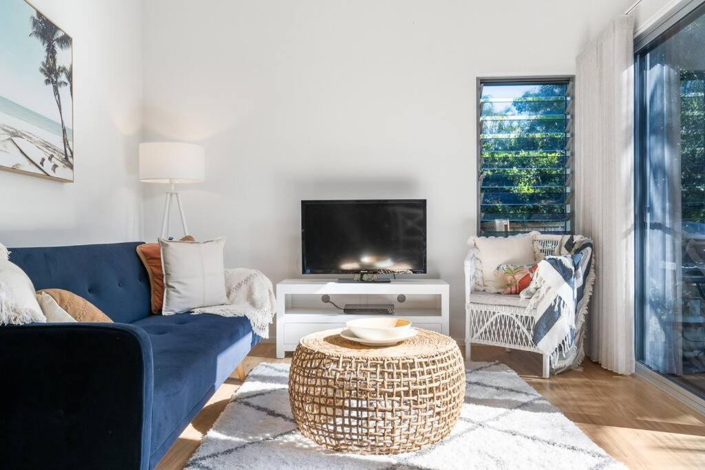 sala de estar con sofá azul y TV en Marie's Byron Getaway en Byron Bay