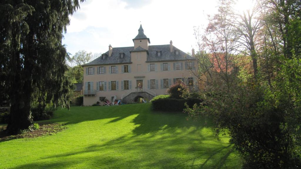 a large house on a green lawn with trees at Chambres d'Hôtes Les Tapies in Agen dʼAveyron