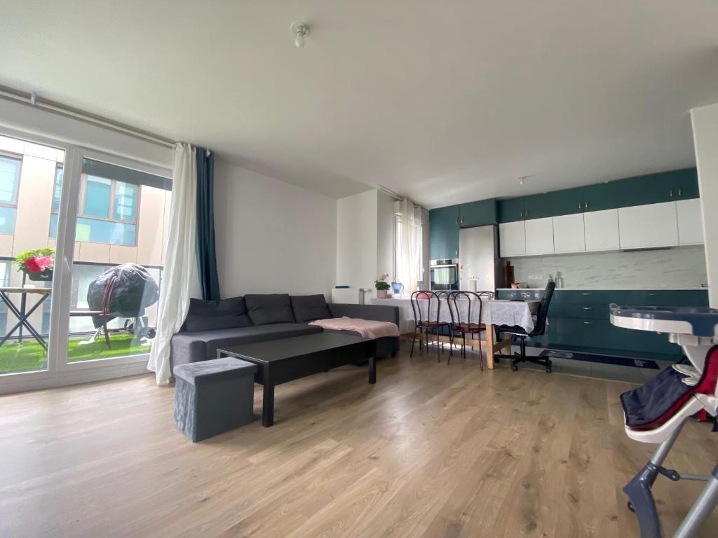 un soggiorno con divano e una cucina di Chambre dans logement neuf, Paris, Disney, Centrex a Noisy-le-Grand