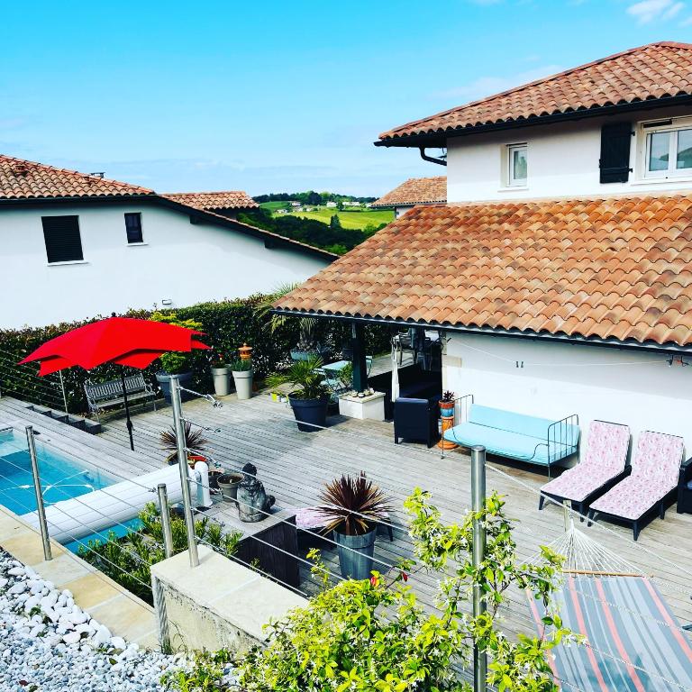une maison avec une piscine et un parasol rouge dans l'établissement MAISON GANTTIPIENEA, à Ahetze