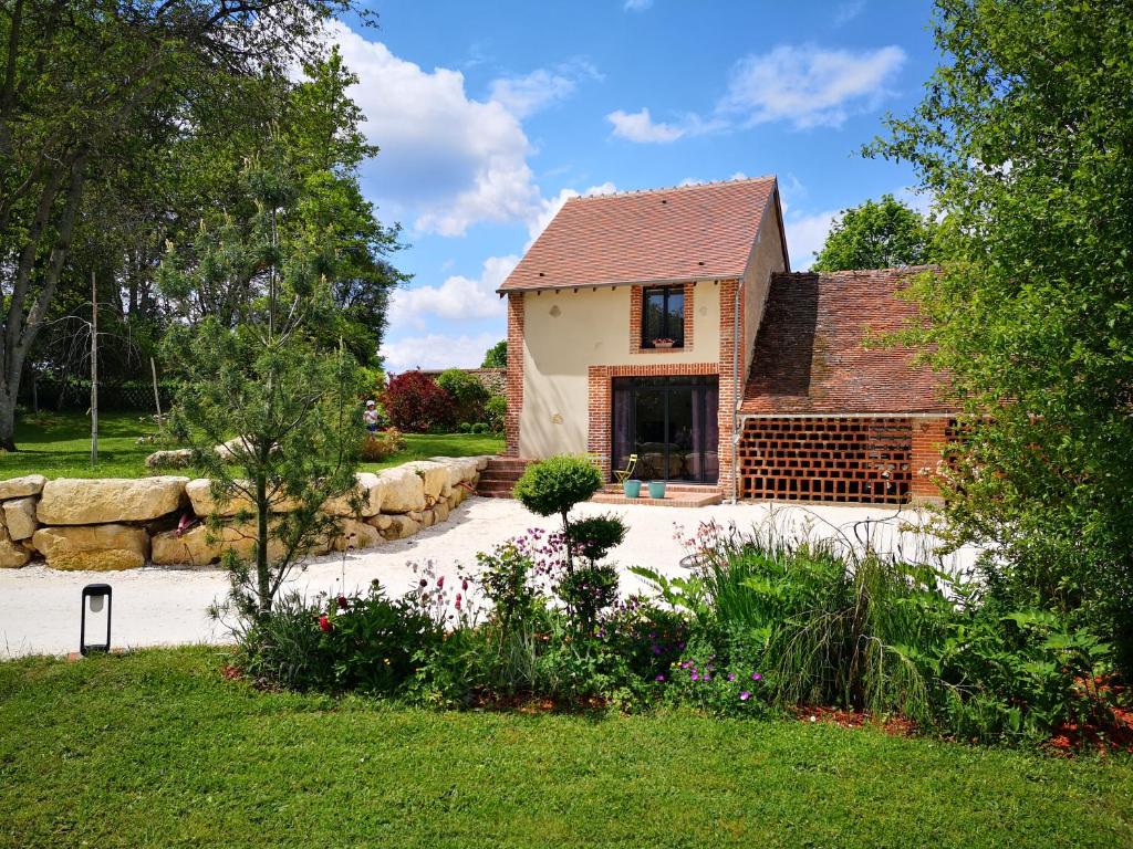 una casa con una pared de piedra y un patio en TUILERIE DE LA COTE 4* en Ouzouer-sur-Trézée