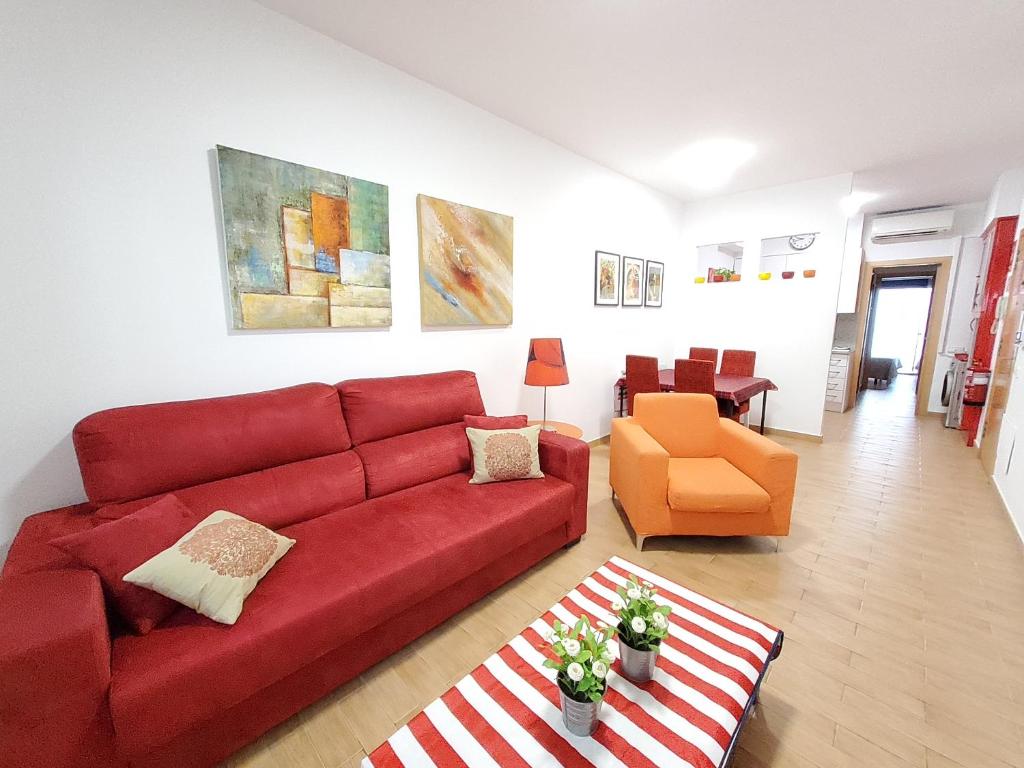 シッチェスにあるApartment Sant Sebastiàのリビングルーム(赤いソファ、オレンジの椅子付)