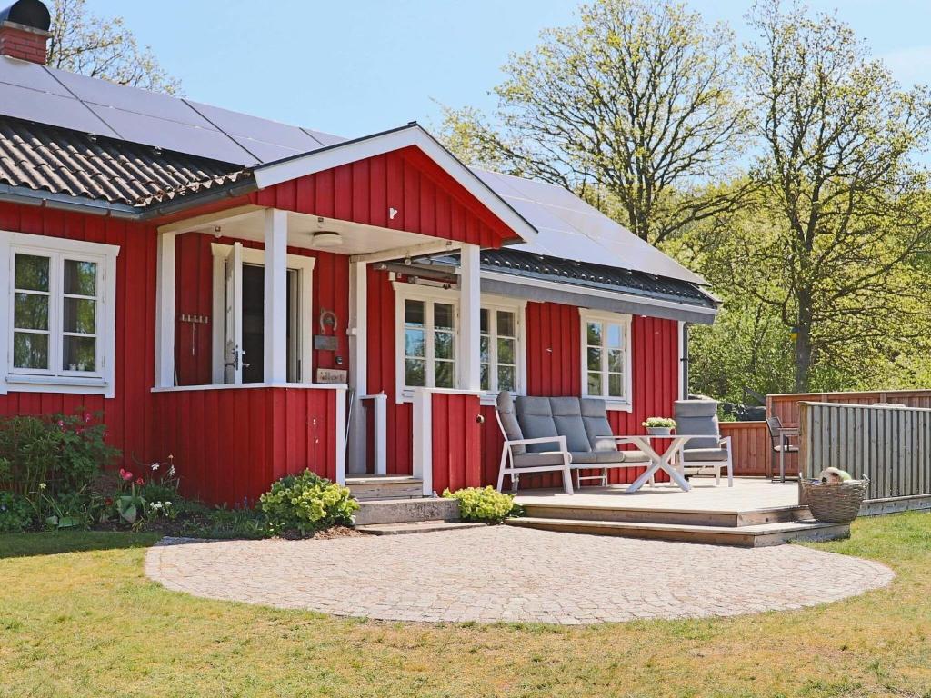une petite maison rouge avec une terrasse et des chaises dans l'établissement 6 person holiday home in Sl inge, à Slöinge