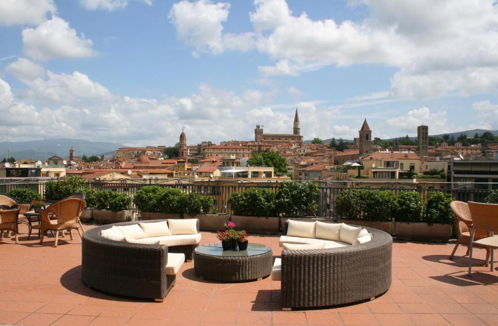 a patio area with chairs, tables, and tables with umbrellas at Hotel Continentale in Arezzo