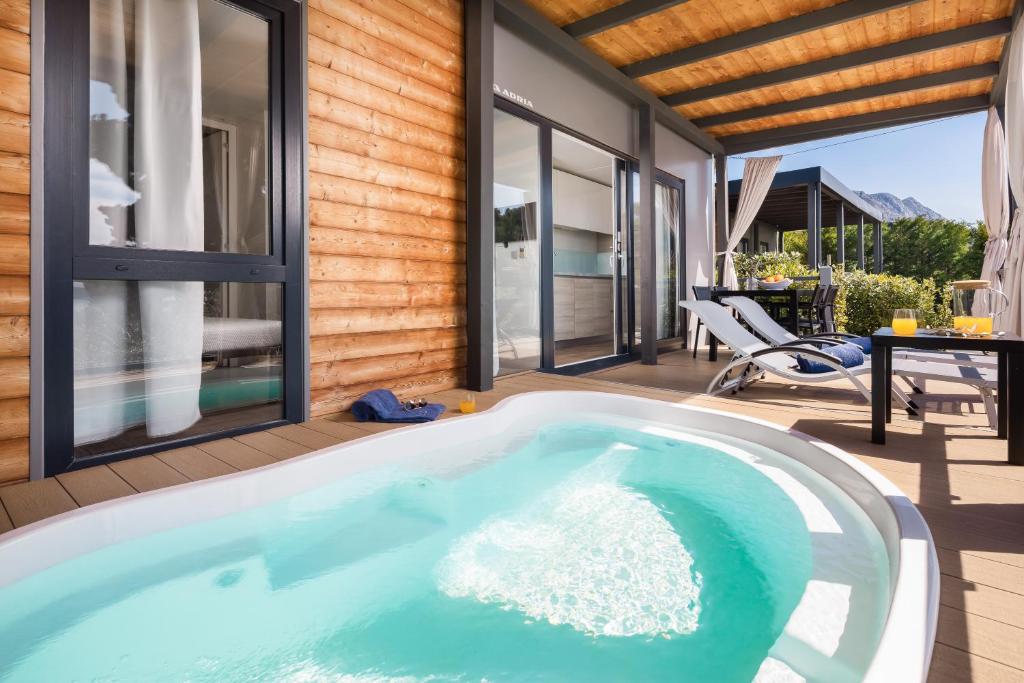 a hot tub in a house with a patio at Medora Orbis Mobile Homes & Glamping in Podgora