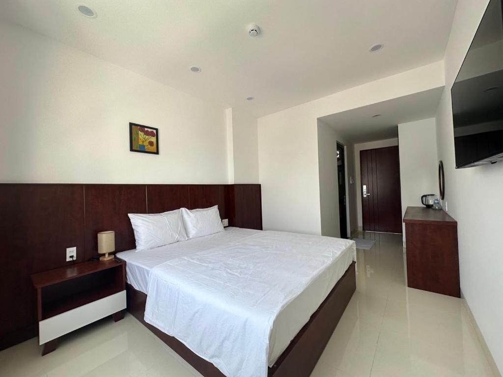 ein Schlafzimmer mit einem großen weißen Bett und einem TV in der Unterkunft FELIZ VILLA NHA TRANG in Nha Trang