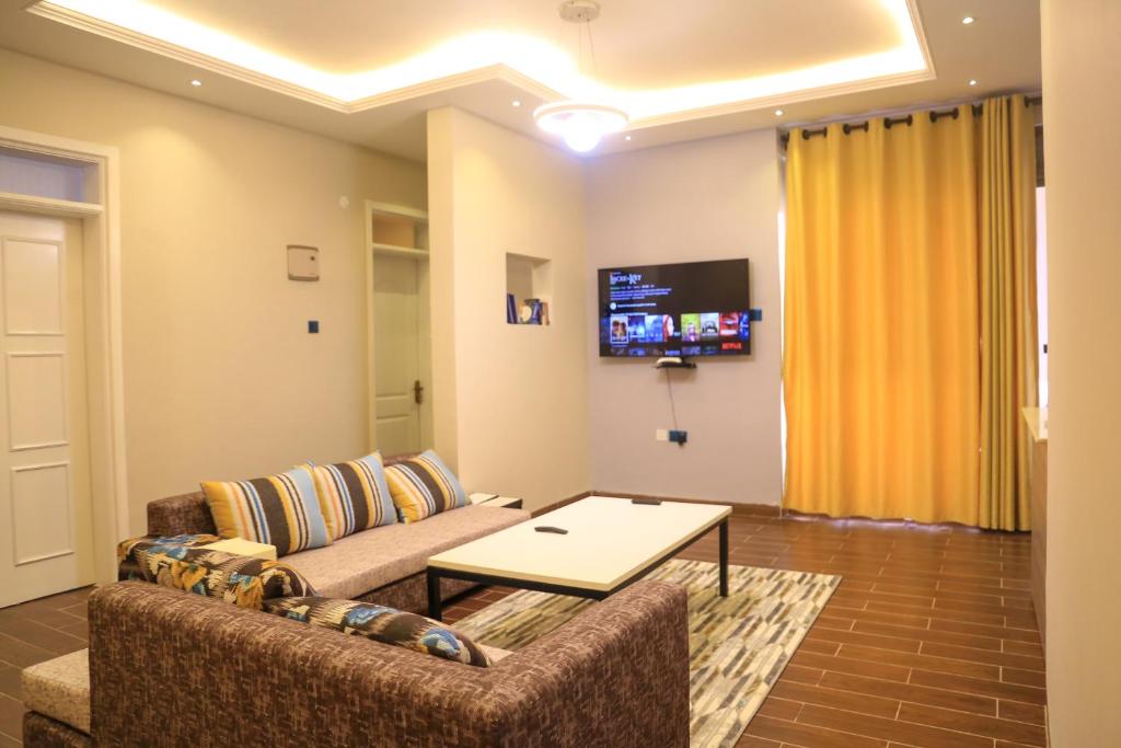 uma sala de estar com um sofá e uma mesa em Gaiety Place Apartments em Kampala