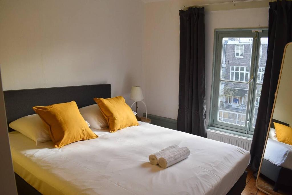 Un dormitorio con una cama con almohadas amarillas y una ventana en Private 4P top floor - hostel apartment en Ámsterdam