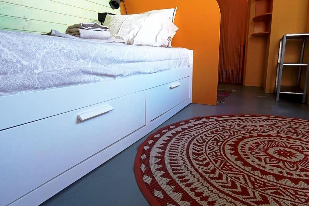 a bedroom with a white bed and a red rug at Private small studio in Costa de Caparica in Costa da Caparica