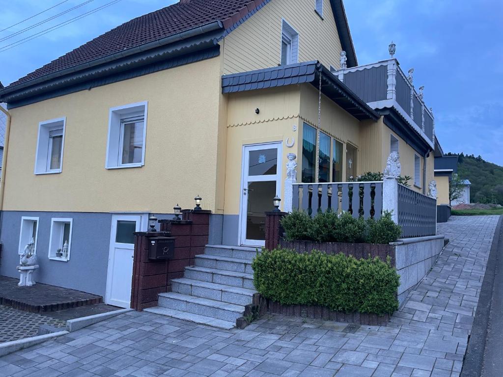 a yellow house with stairs in front of it at Ferienwohnung Anna in Hoppstädten-Weiersbach