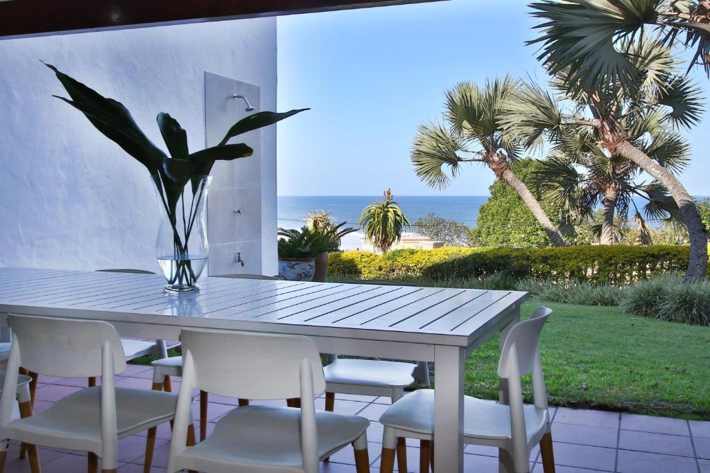 a dining table and chairs with a view of the ocean at Shorebreak in Southbroom