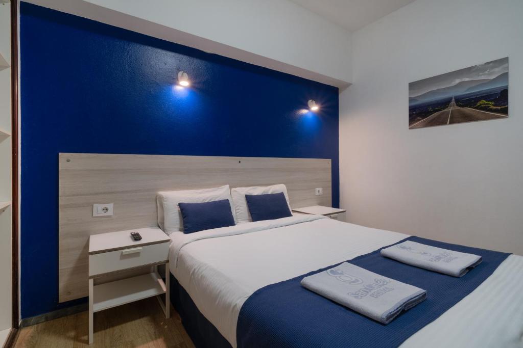1 dormitorio con 1 cama grande y pared azul en Hostal San Ginés, en Arrecife