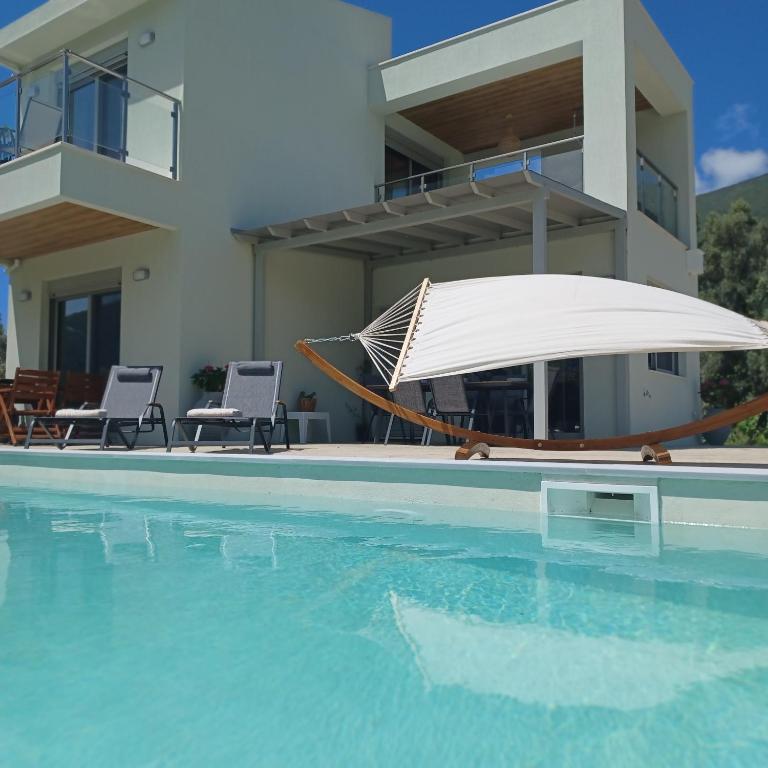 a house with a swimming pool with a hammock and a house at Dream Time Villa Vasiliki in Vasiliki
