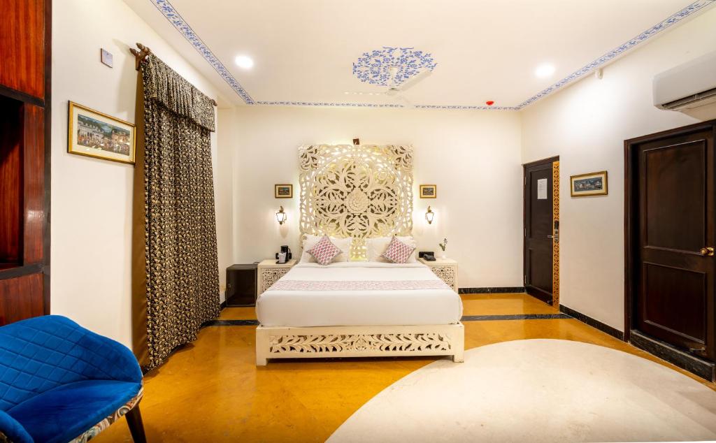 een slaapkamer met een kingsize bed en een blauwe stoel bij The Chronicles Hotel in Udaipur