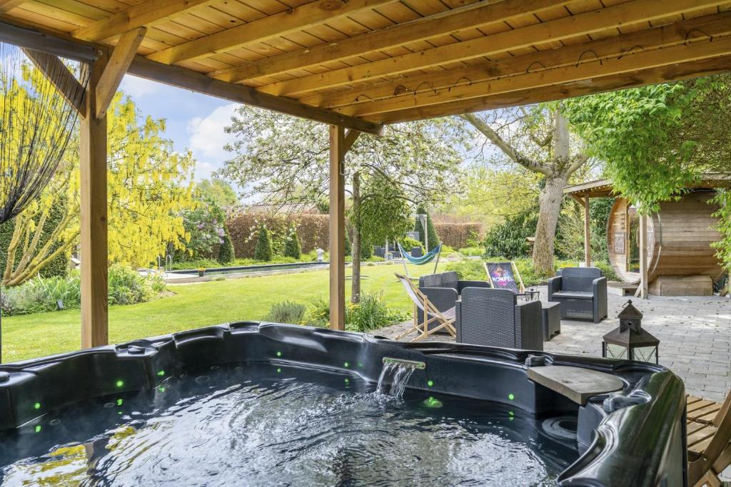 a hot tub in a backyard with a pergola at Maas&Mechelen B&B Massage & Wellness in Maasmechelen