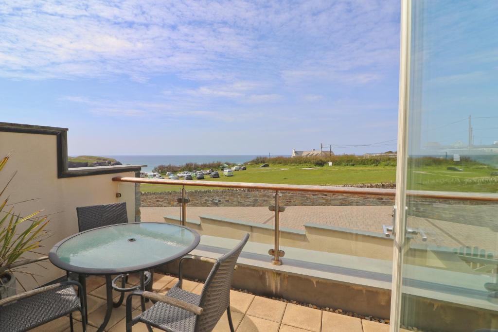 een balkon met een tafel en stoelen en uitzicht op de oceaan bij SEA VIEWS, beachside apartment with balcony in Saint Merryn