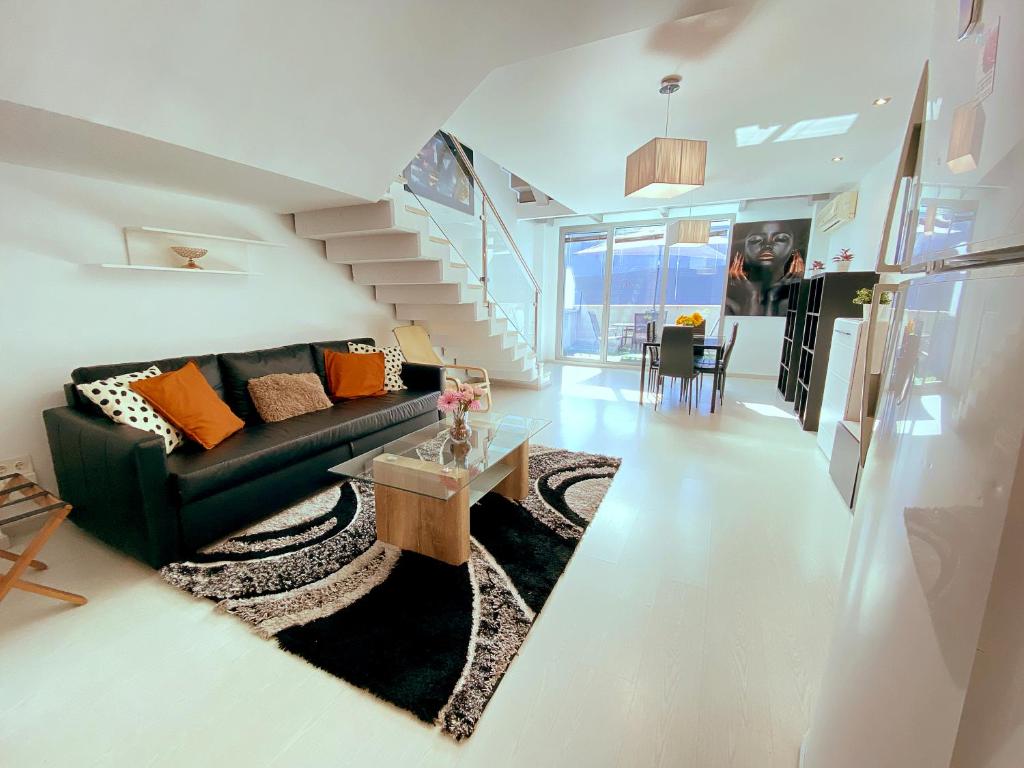 a living room with a black couch and a staircase at Madrid Norte II by Oshun Apartments in Madrid