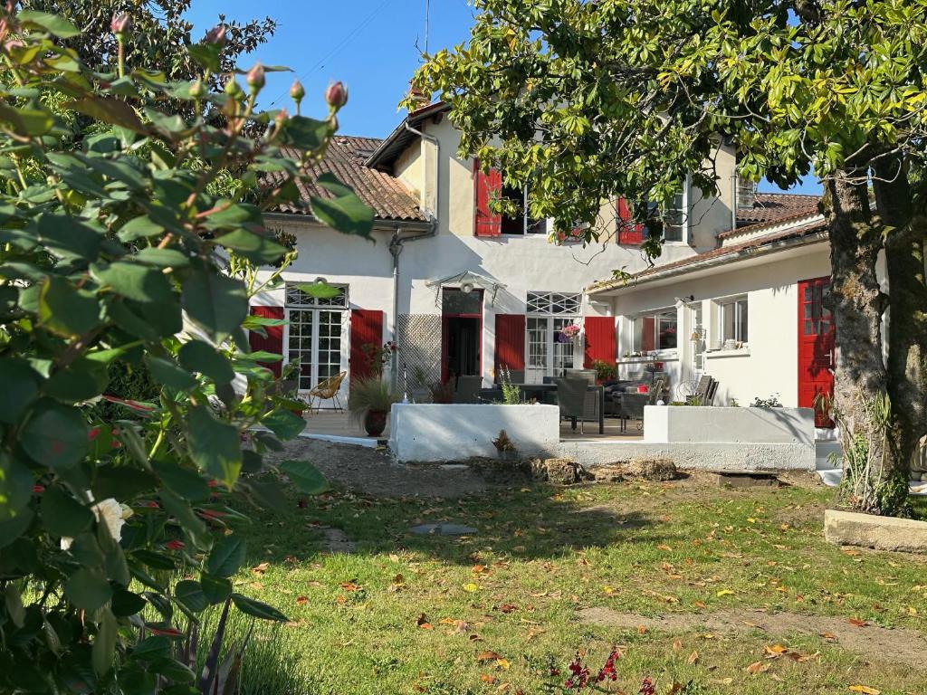 una casa blanca con una puerta roja y un patio en La Maison Florence, en Mont-de-Marsan