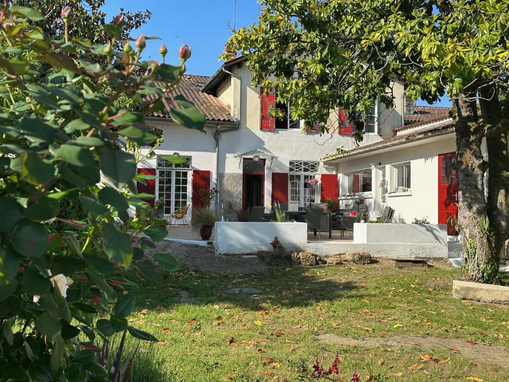 a white house with a red door and a yard at La Maison Florence in Mont-de-Marsan