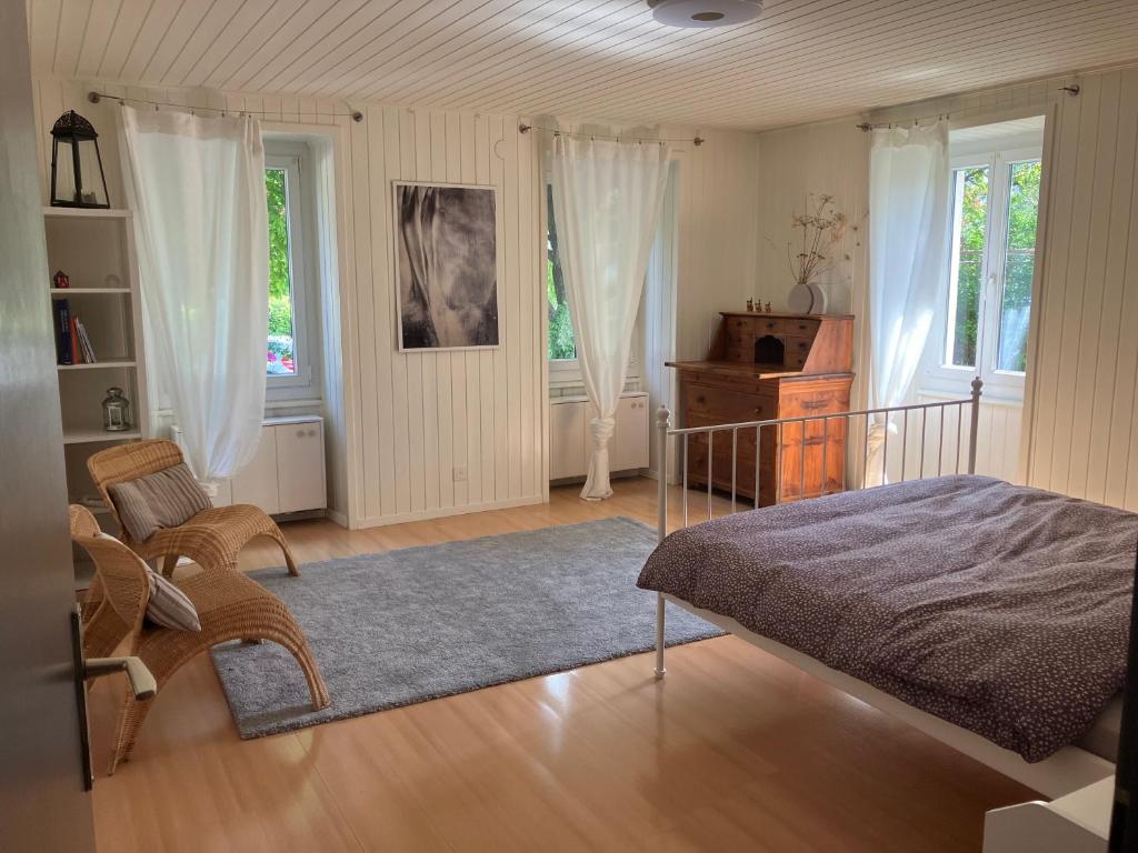 a bedroom with a bed and a chair and windows at La Lanterne in Sierre