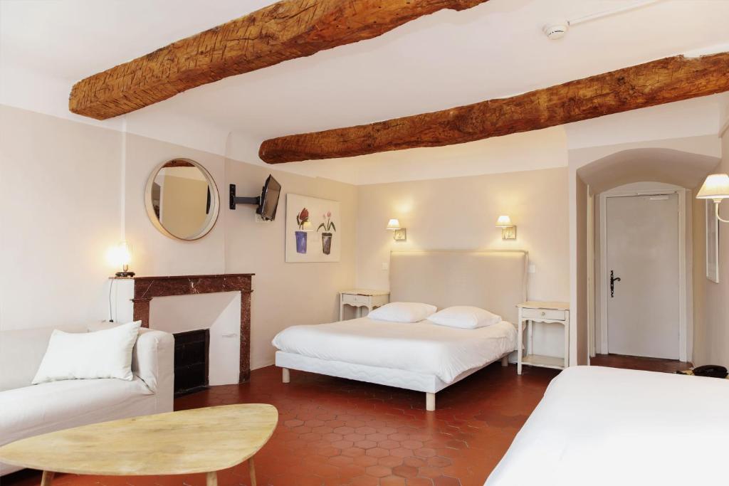 a bedroom with two beds and a fireplace at Coq Hotel in Cogolin