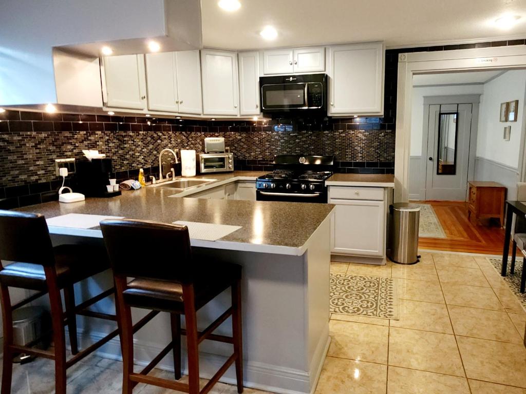 a kitchen with white cabinets and a island with bar stools at RED DOOR HOUSE in Lakeland