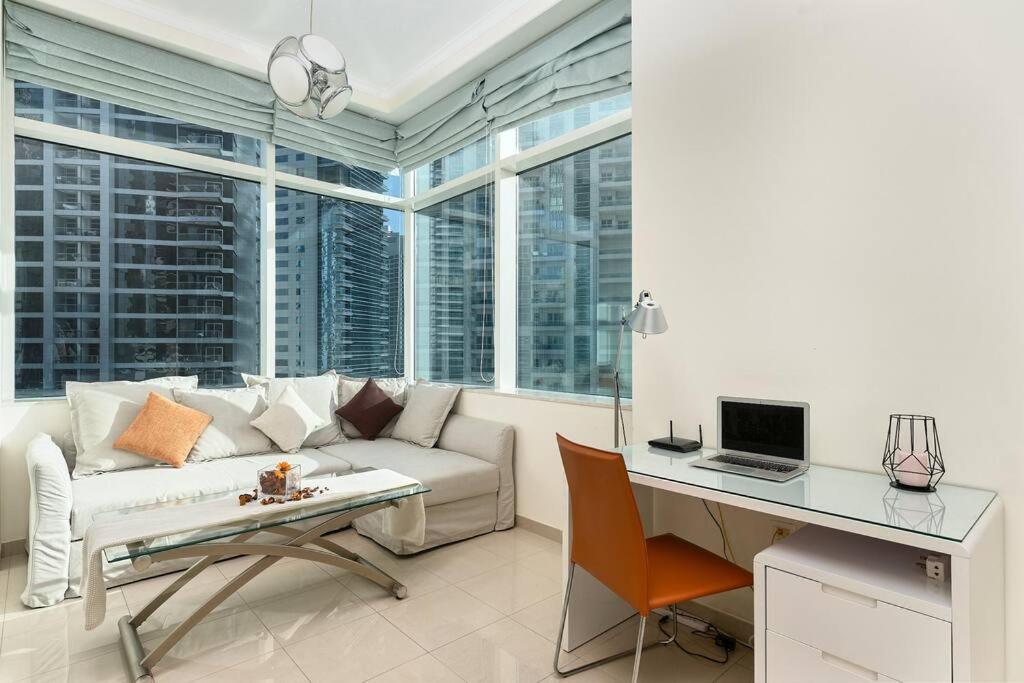 een woonkamer met een bank en een bureau met een laptop bij Beautiful 1BR with sunset view Dubai Marina in Dubai