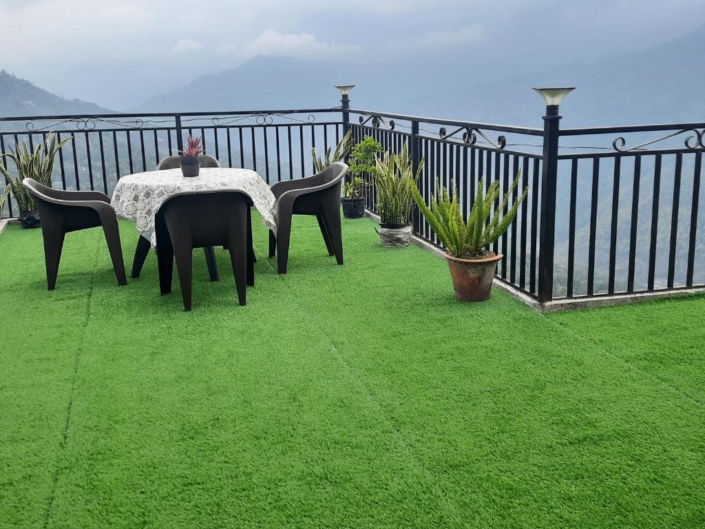 un tavolo e sedie su un balcone con prato verde di The Sangam Homestay a Kalimpong