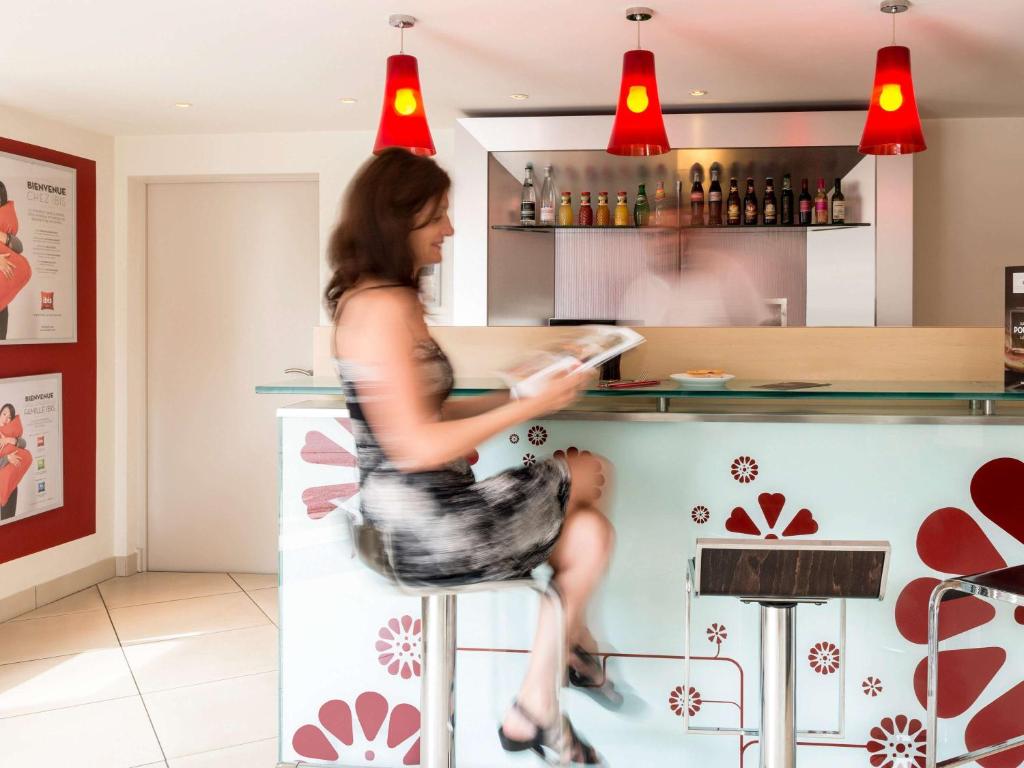 a woman sitting on a stool at a bar at Hôtel Ibis Cognac Centre in Cognac